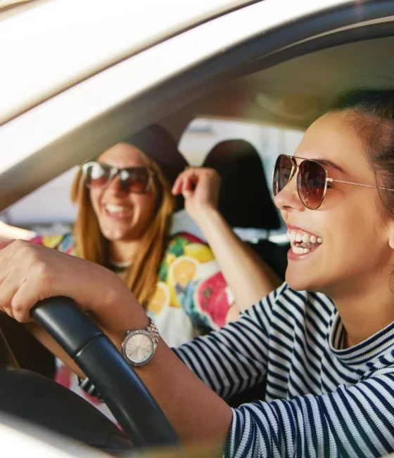 two friends smiling in car driving