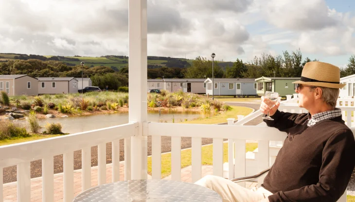 Senior citizen sits on porch of mobile home.