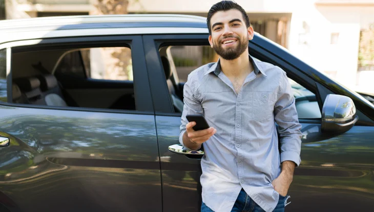 Male rideshare driver standing out front of car.