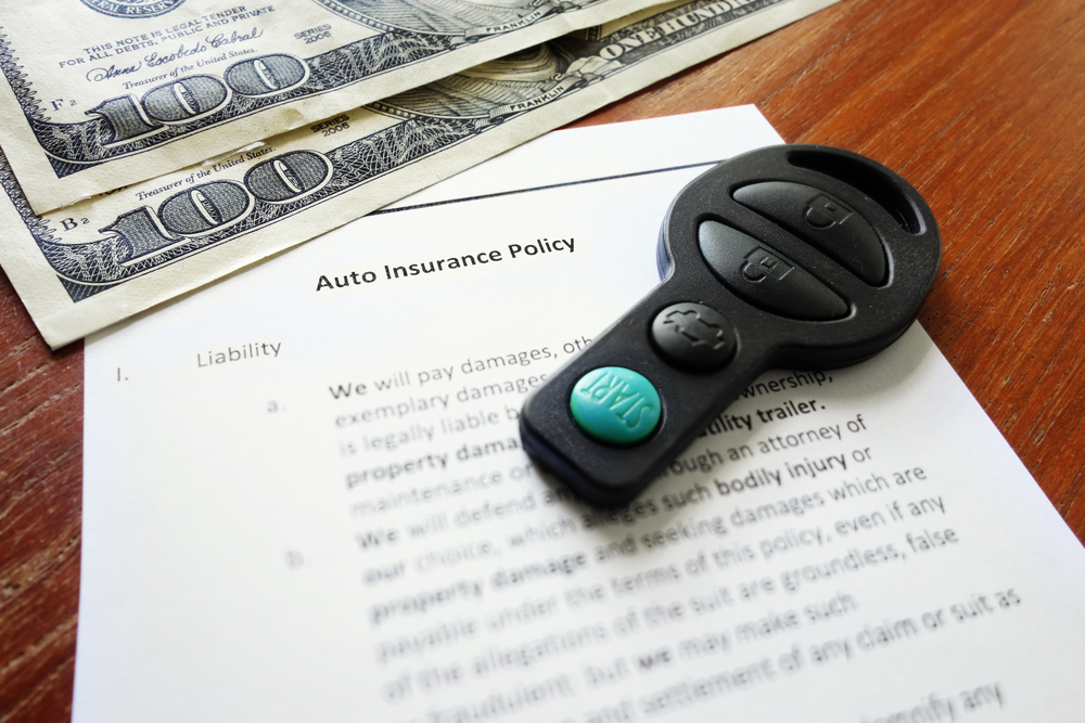 auto insurance policy document with money and car key fob