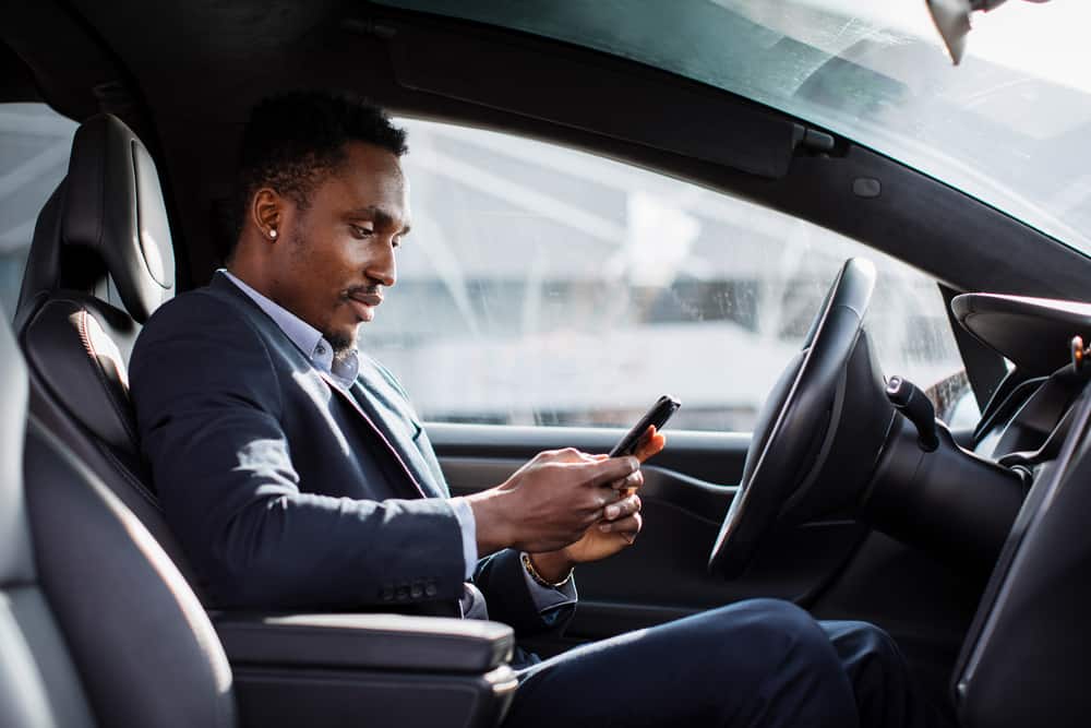 man stopped in car on phone behind wheel