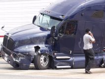 Truck drivers stands beside his semi talking on the phone after a wreck, cheap commercial truck insurance in Georgia.