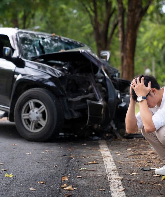 Young man on side of the road with head in hands because his truck is crashed into a tree - cheap car insurance in Georgia.