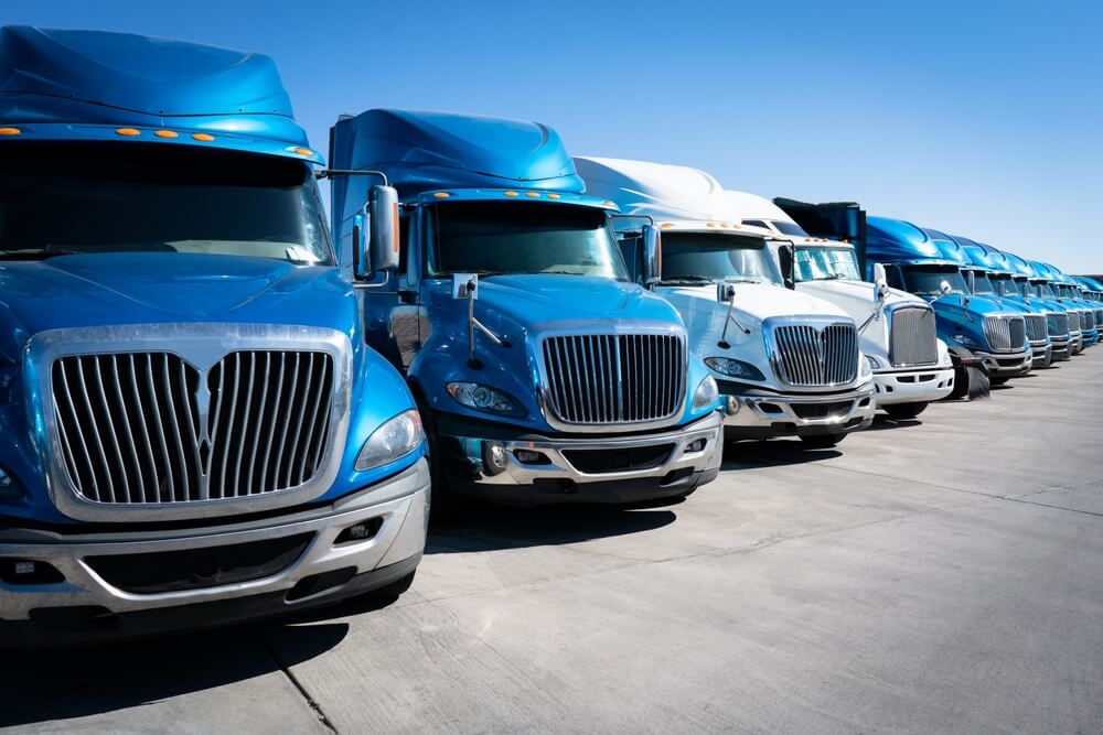 Line of blue and white semitrucks covered by commercial auto insurance - Cheap auto insurance in Georgia 