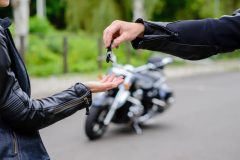 Male motorcyclist handing keys to unlicensed female biker - Velox, Cheap Motorcycle Insurance in Georgia