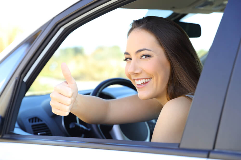 Female driver smiling and giving a thumbs up for having cheap car insurance in Georgia
