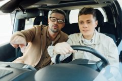 Father pointing on something while teaching teen son driving car - Velox, cheap auto insurance in Georgia