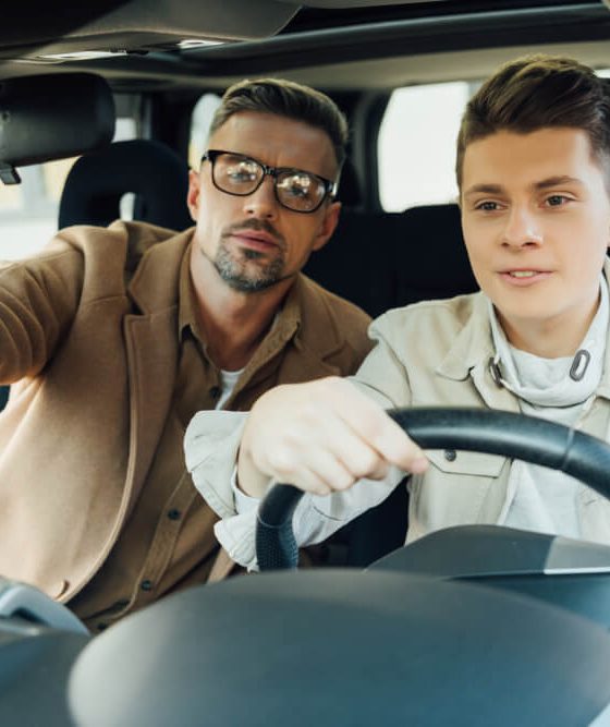 Father pointing on something while teaching teen son driving car - Velox, cheap auto insurance in Georgia