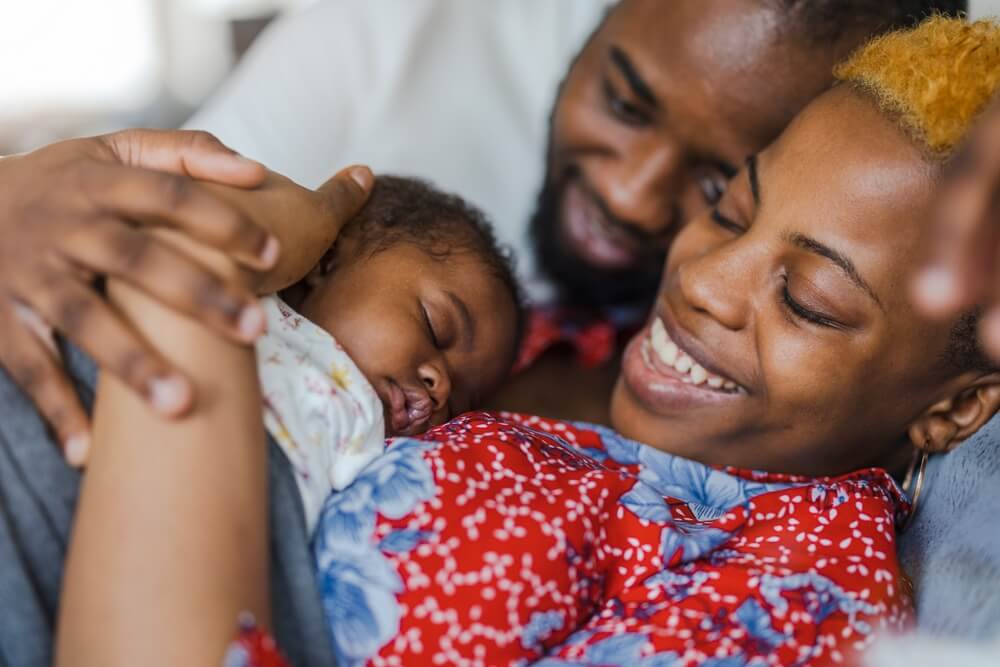 Happy couple embraces their new baby.