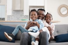 African-American father with his two children playing in the living room.