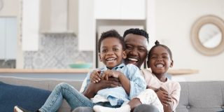 African-American father with his two children playing in the living room.