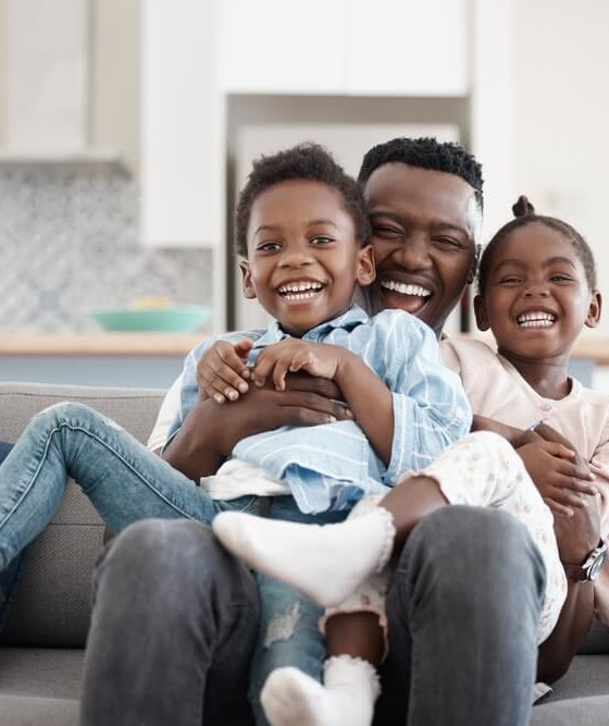 African-American father with his two children playing in the living room.