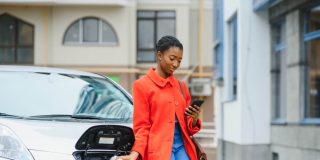 A young female charges up her electric vehicle - cheap insurance in Atlanta, GA.