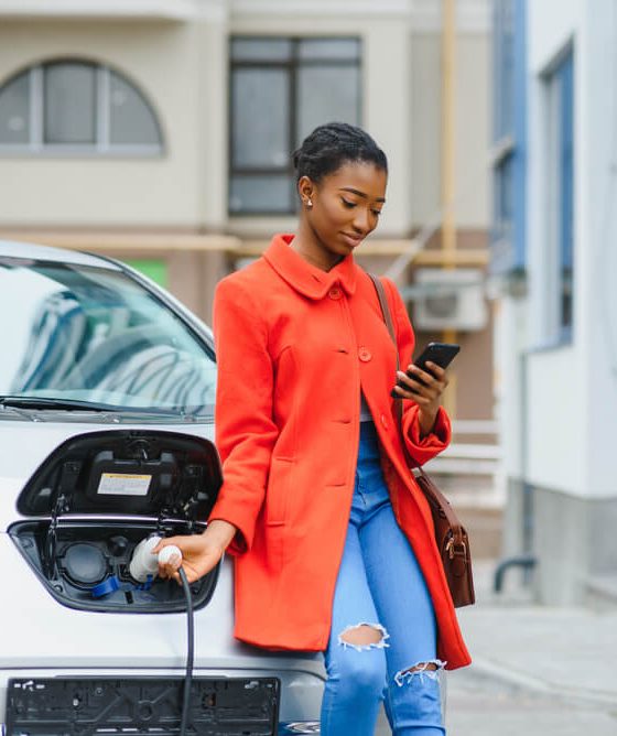 A young female charges up her electric vehicle - cheap insurance in Atlanta, GA.