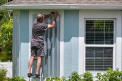 Putting up storm windows before a major storm hits - cheap homeowners insurance in Georgia.