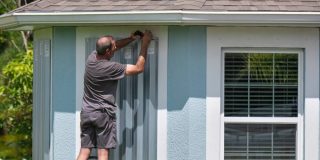 Putting up storm windows before a major storm hits - cheap homeowners insurance in Georgia.