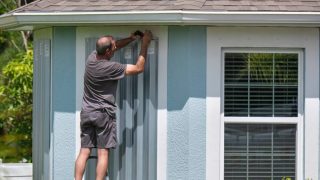 Putting up storm windows before a major storm hits - cheap homeowners insurance in Georgia.