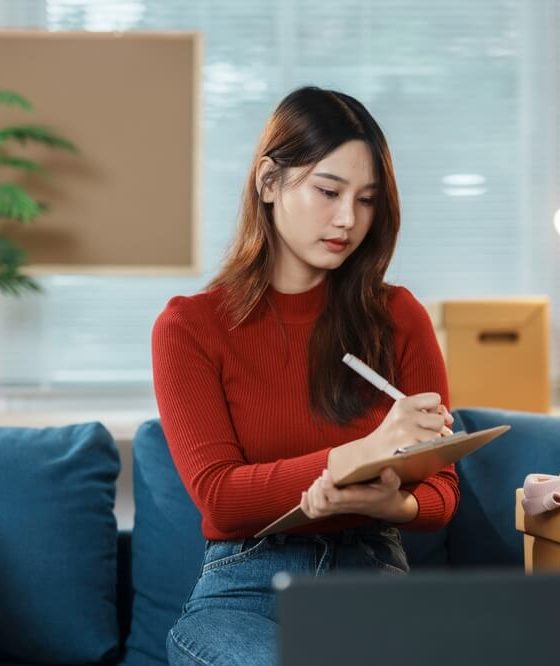 Woman sits on couch and conducts a home inventory of her belongings - cheap home insurance in Georgia.