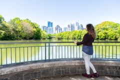 Woman in Piedmon Park in Atlanta looks at Atlanta skyline - cheap car insurance in Georgia.