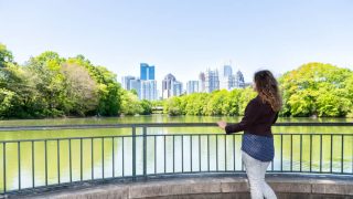 Woman in Piedmon Park in Atlanta looks at Atlanta skyline - cheap car insurance in Georgia.