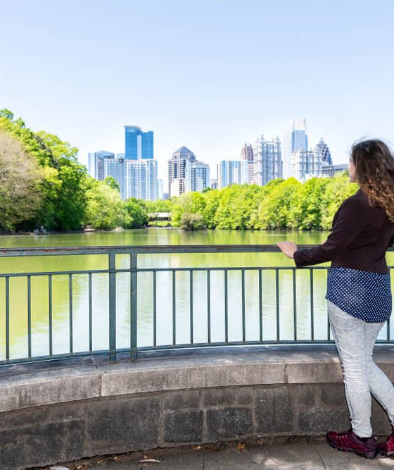 Woman in Piedmon Park in Atlanta looks at Atlanta skyline - cheap car insurance in Georgia.