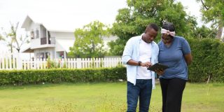 A couple stands in a field next to their high-end home - cheap home insurance in Georgia.