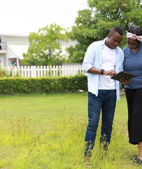 A couple stands in a field next to their high-end home - cheap home insurance in Georgia.