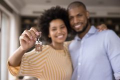 A young couple smiles and the woman holds up the keys to their new home - cheap homeowners insurance in Georgia.