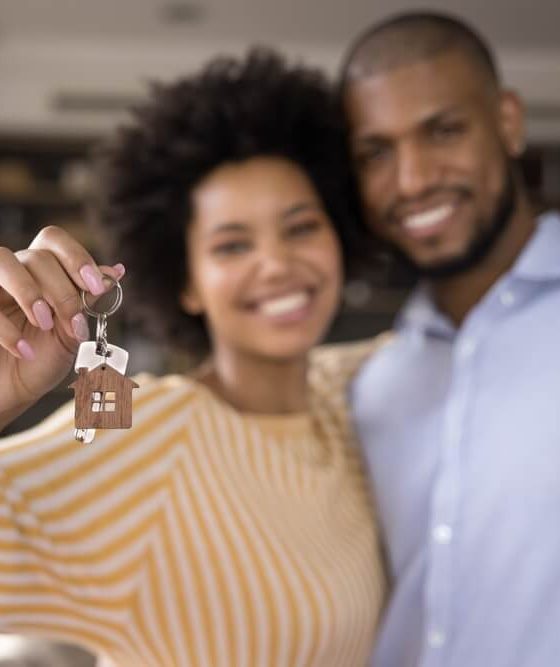 A young couple smiles and the woman holds up the keys to their new home - cheap homeowners insurance in Georgia.