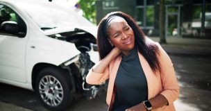 A woman rubs her neck after being involved in a car accident.