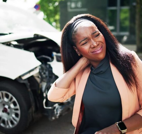 A woman rubs her neck after being involved in a car accident.