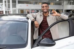 A smiling man shows off the car he has for sale in Georgia.