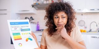 A woman is not happy about her low credit score she is holding on a colored print out.