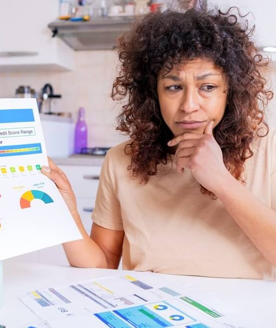 A woman is not happy about her low credit score she is holding on a colored print out.