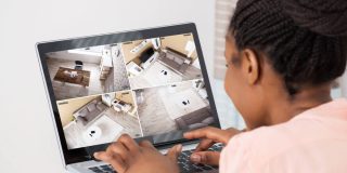 A woman monitors her home while on vacation through her laptop - cheap home insurance in Georgia.
