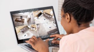 A woman monitors her home while on vacation through her laptop - cheap home insurance in Georgia.