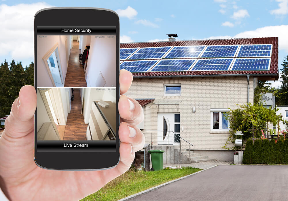 A hand holds a smart phone that tracks the security inside the home - cheap home insurance in Georgia.