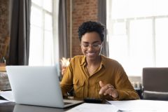 Business woman sits at her computer, smiling, because her business is protected with business insurance in Georgia.