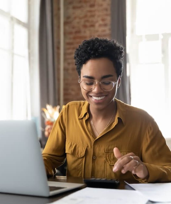 Business woman sits at her computer, smiling, because her business is protected with business insurance in Georgia.