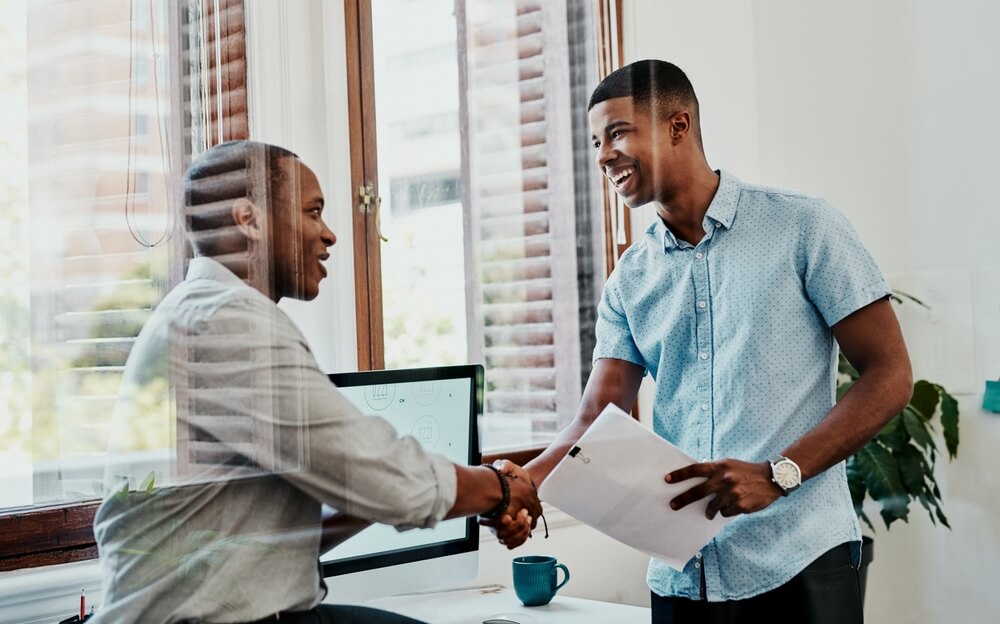 Two businessmen shake hands, concept of purchasing business insurance.