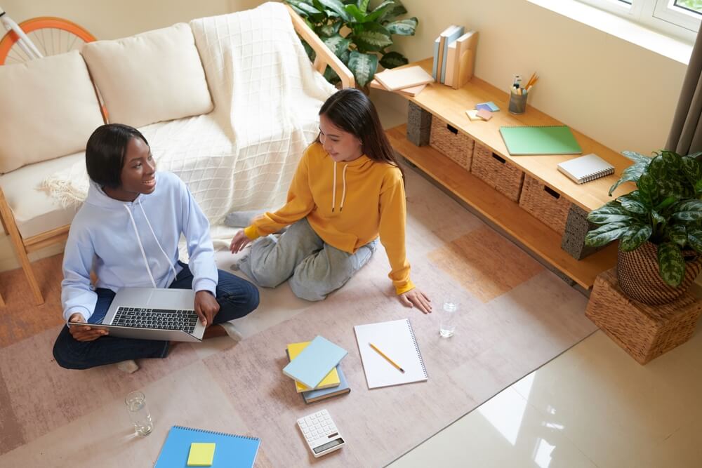 Diverse college students sitting on the floor in rented room and discussing big project they were working on, renting out a room in your Georgia house to a student.