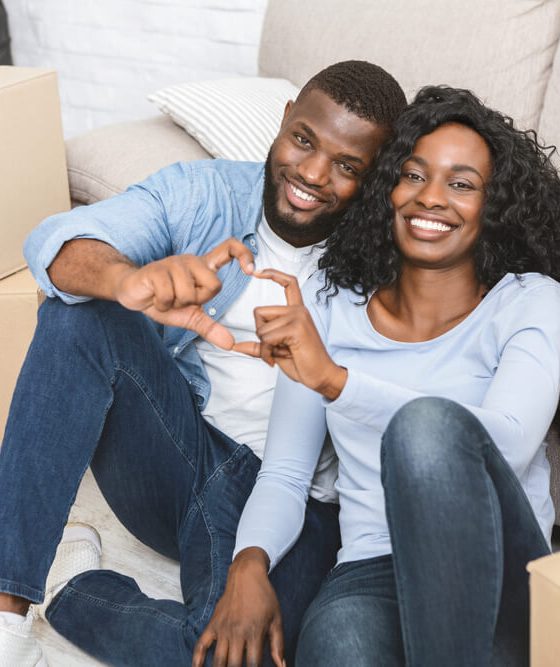 Young couple sits among the boxes, moving into their new home, building up home equity and using home insurance to help.