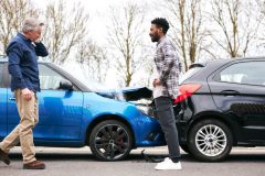 Senior and younger male drivers get out of cars and inspect damage after road traffic accident, what to do after a car accident, cheap car insurance in Georgia.