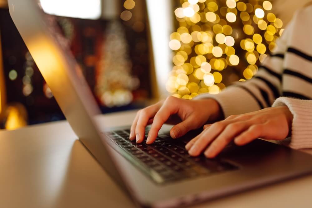 Person typing on a laptop in a cozy space with holiday lights, representing a business in Georgia protected by insurance