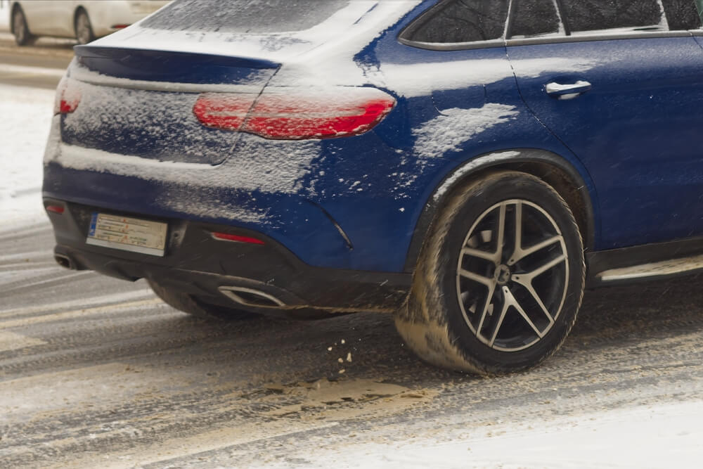 A car on slippery road during heavy snowfall, slippery road and difficult road conditions, winter driving conditions and the impact of holiday driving on car insurance rates.