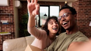 New homeowner couple holding their key and a box just moved in and purchased homeowners insurance