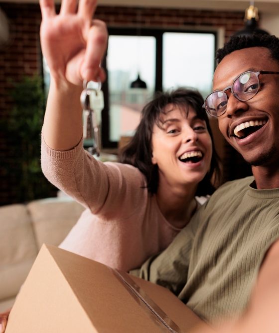 New homeowner couple holding their key and a box just moved in and purchased homeowners insurance