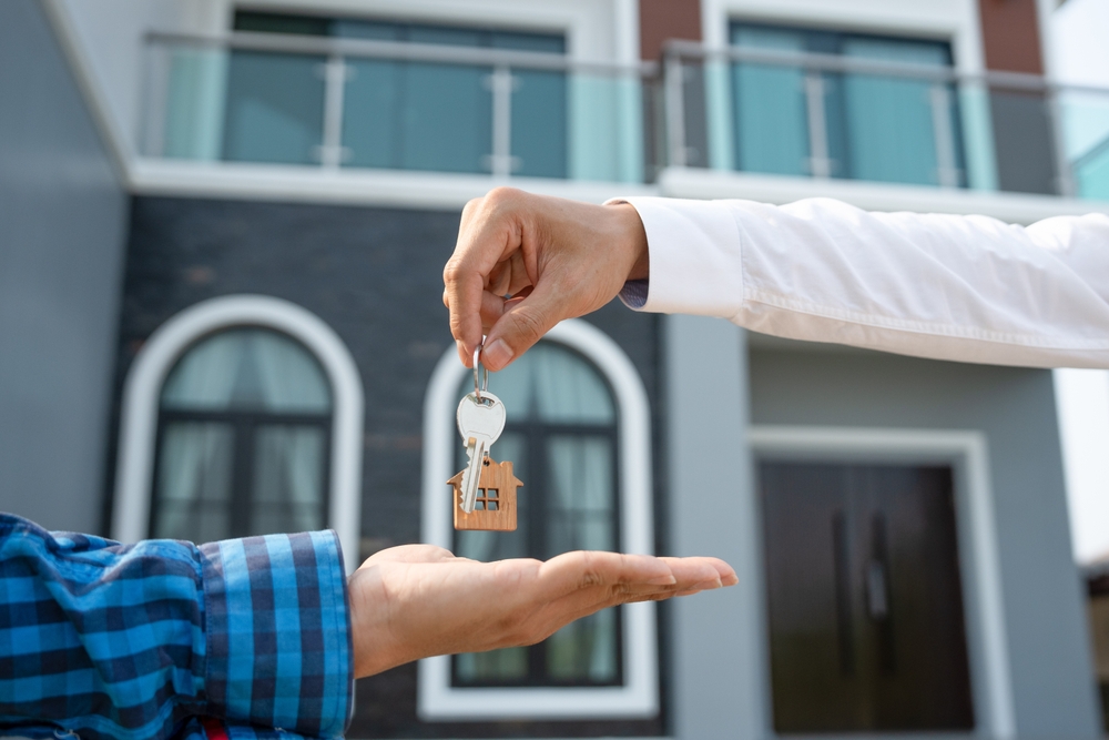 Real estate landlord holding key for new renter, protected with landlord’s insurance.
