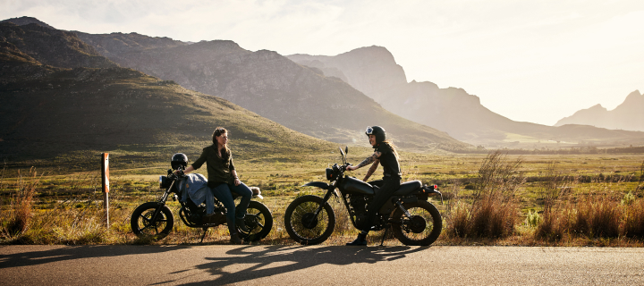 Two people on their motorcycles on the highway.