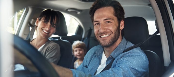 Family smiling aboard their car.